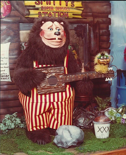 The earlier, more wrinkly and furry version of the Billy Bob animatronic. He is a fat brown bear with red and yellow vertically striped overalls and a handmade wooden bass.
