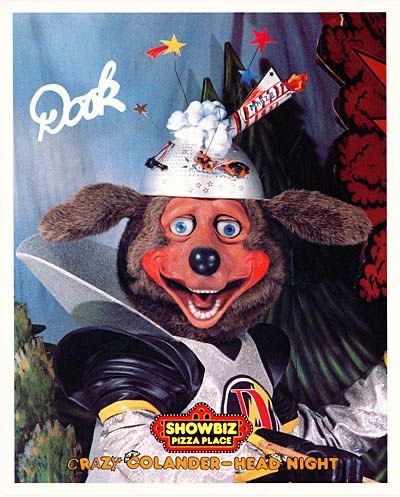 the dook larue animatronic smiling at the camera in a decorated rocket colander. There is his signature, the showbiz logo and text saying 'crazy colander head night.'
