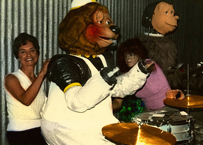 Two women putting cosmetics on an unfinished rockafire, with dook in the focus.