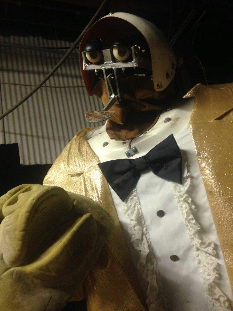 The fatz animatronic with an exposed face mech and an unpainted mask next to him.