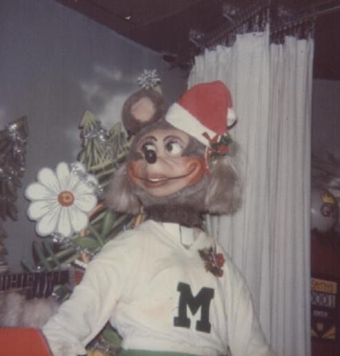 Mitzi animatronic with short pigtails and a Christmas hat.
