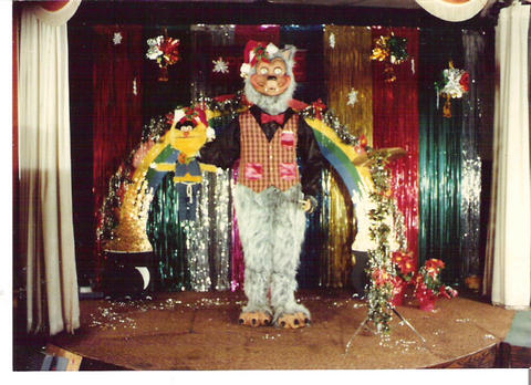 Rolfe animatronic in a santa hat with his stage decorated with christmas decor.